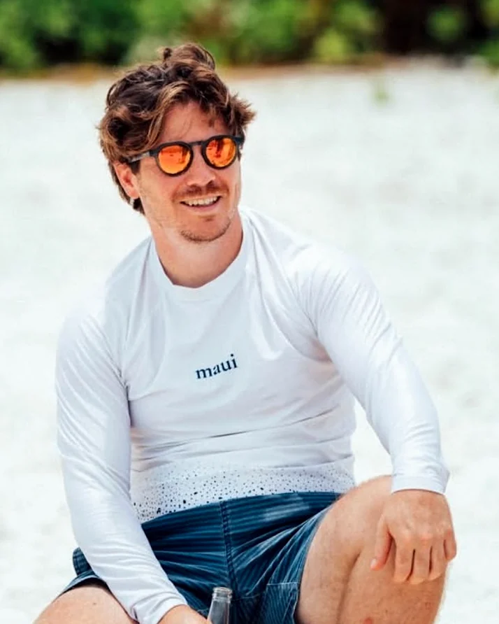 Man on the sand wearing a white custom long-sleeve rashguard with the Maui logo, made by Sportswear of Tomorrow