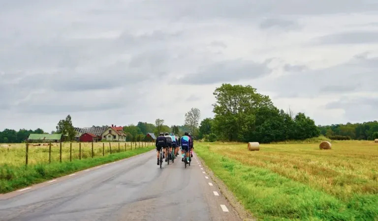 Group of road cyclists riding along a quiet country road in custom cycling kit