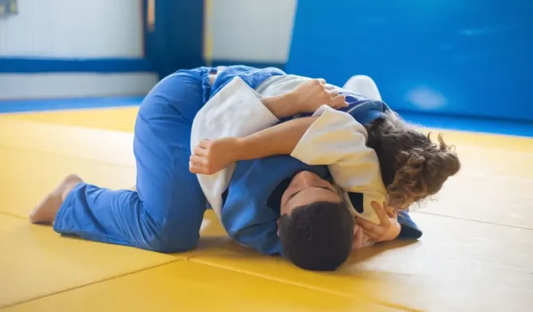 Two athletes grappling on a training mat, the setting a BJJ rashguard brand designs for