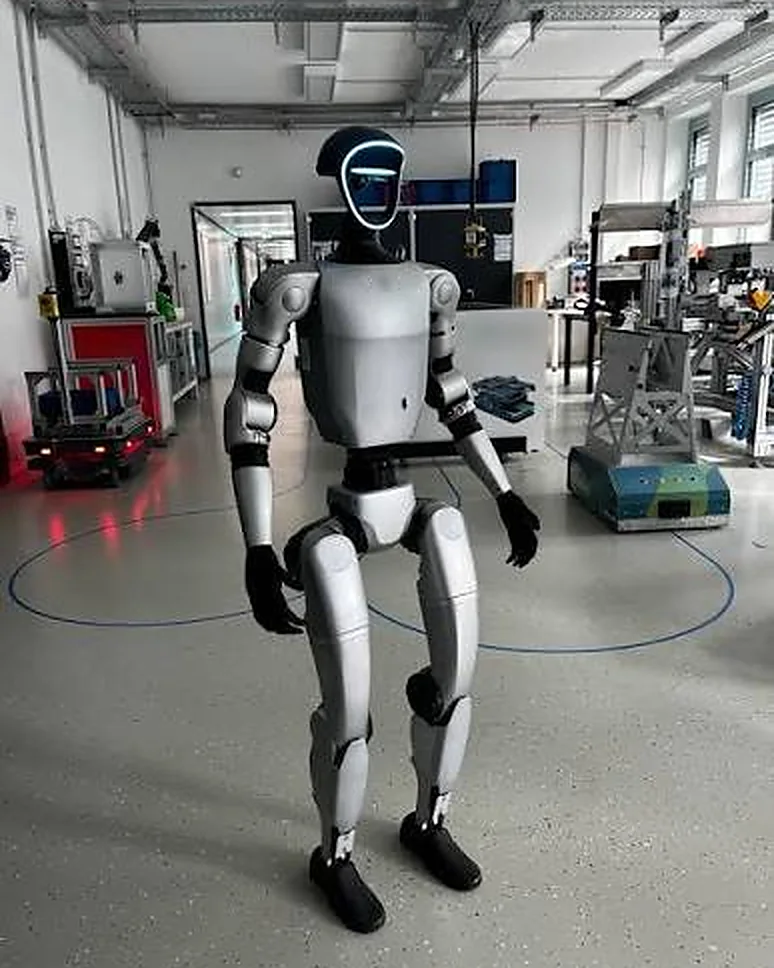 Humanoid robot with a glowing ring face standing in a robotics lab